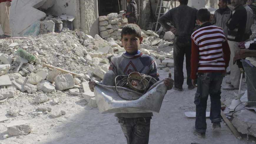 A boy collects his belongings amidst the rubble of collapsed buildings after what activists said was shelling by forces loyal to Syria's President Bashar al-Assad in Aleppo November 24, 2013.  Air strikes around the northern Syrian city of Aleppo killed at least 40 people on Saturday, most of them civilians, the Syrian Observatory for Human Rights said. REUTERS/Molhem Barakat (SYRIA - Tags: POLITICS CIVIL UNREST CONFLICT) - RTX15R6Q