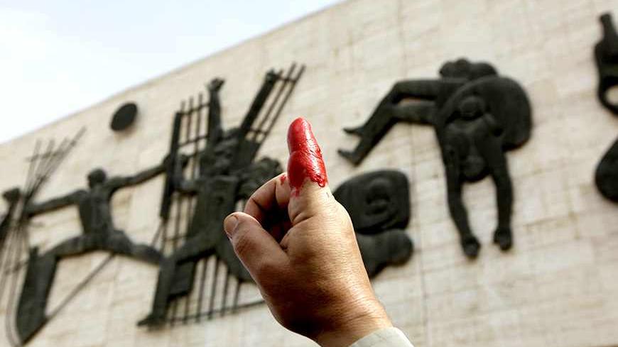 A protester holds up his red-inked finger during a demonstration at Tahrir Square in central Baghdad March 7, 2011. The protesters say they inked their fingers to show their disapproval with the government they elected in March 7, 2010, which they claim have not fulfilled its promises.     REUTERS/Saad Shalash (IRAQ - Tags: CIVIL UNREST POLITICS) - RTR2JKMV