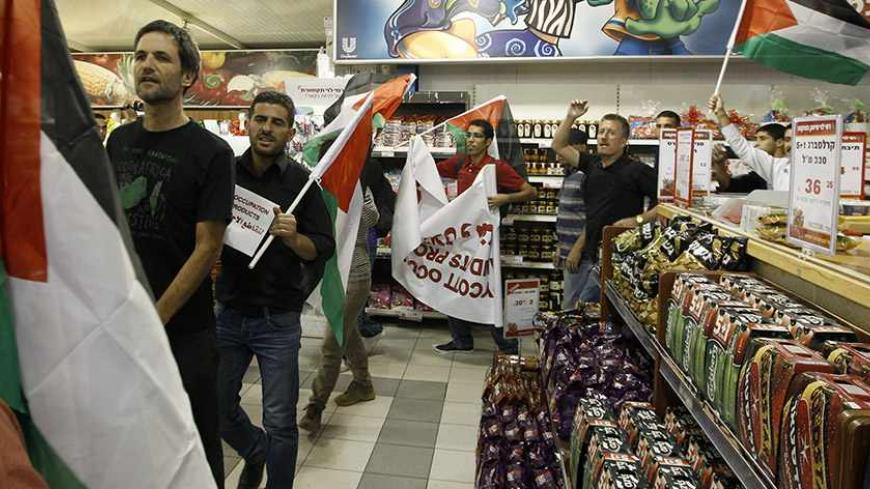 Foreign and Palestinian activists hold Palestinian flags as they march through a supermarket in the West Bank Jewish settlement of Modiin Illit October 24, 2012. Some 50 activists marched through the supermarket and tried to block a road in the settlement on Wednesday during a protest against Jewish settlements and in a call to boycott settlement products. REUTERS/Ammar Awad (WEST BANK - Tags: POLITICS CIVIL UNREST FOOD TPX IMAGES OF THE DAY) - RTR39IM8