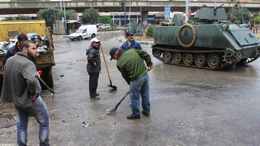 People clean the streets as the Lebanese army deploys on the streets of the Sunni Muslim Bab al-Tebbaneh neighbourhood in Tripoli, northern Lebanon December 4, 2013. The Lebanese government has told the army to take over security in the restive coastal city of Tripoli for six months, caretaker Prime Minister Najib Mikati said on Monday. Ten people were killed in weekend clashes between Tripoli's Alawite minority, which supports Syria's Alawite President Bashar al-Assad, and majority Sunni Muslims who back h