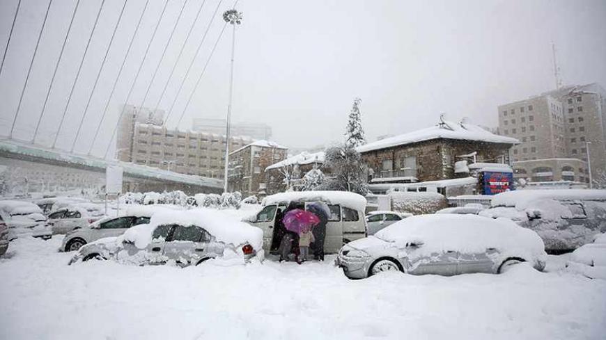 People leave their car during a snowstorm after it was stuck in heavy snowfall in Jerusalem December 13, 2013. A snowstorm of rare intensity blanketed the Jerusalem area and parts of the occupied West Bank on Friday, choking off the city and stranding hundreds in vehicles on impassable roads.  REUTERS/Baz Ratner (JERUSALEM - Tags: ENVIRONMENT) - RTX16GQ1
