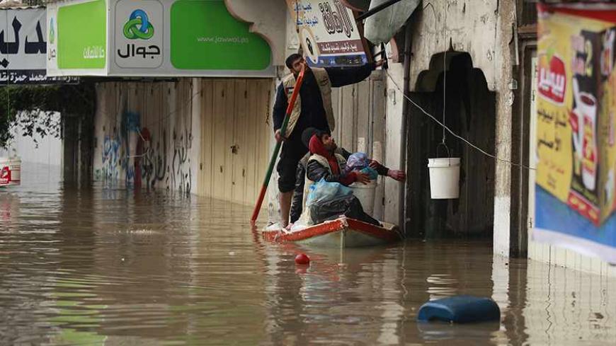 Palestinians man a boat carrying food supplies, to be passed to people whose houses were flooded with rainwater on a stormy day, in the northern Gaza Strip December 14, 2013. Northern Gaza Strip has become a disaster area following an icy storm that led to the evacuation of hundreds of Palestinian families from their flooded houses to UNRWA facilities, Chris Gunness, UNRWA spokesman, said. REUTERS/Mohammed Salem (GAZA - Tags: ENVIRONMENT SOCIETY TPX IMAGES OF THE DAY) - RTX16HYD