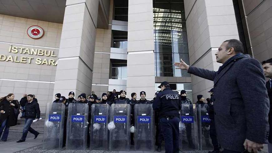 A plainclothes police officer reacts as riot police stand guard in front of the courthouse in Istanbul December 20, 2013. Turkish police arrested eight people in connection with allegations of official corruption and bribery, a newspaper said on Friday, in an investigation Prime Minister Tayyip Erdogan has called a "dirty operation" aimed at undermining his rule. REUTERS/Osman Orsal (TURKEY - Tags: POLITICS CRIME LAW) - RTX16PID