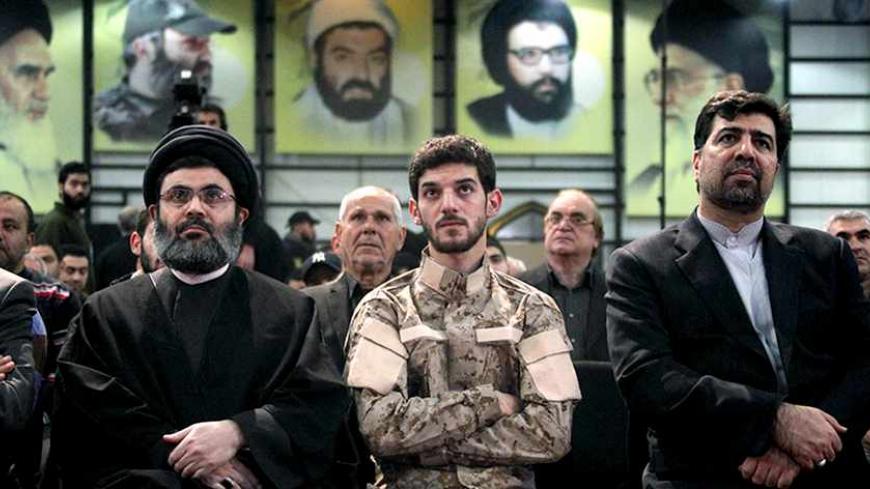 (L-R) Sayyed Hashem Safieddine, head of Hezbollah's Executive Council, sits next to the Hussein al-Laqqis, the son of Hezbollah commander Hasan al-Laqqis, and Iran's Ambassador to Lebanon Ghazanfar Roknabadi as they listen to Lebanon's Hezbollah leader Sayyed Hassan Nasrallah (unseen) via a screen during a ceremony to mark the death of Hezbollah commander Hasan al-Laqqis in Beirut's southern suburbs December 20, 2013. REUTERS/ Sharif Karim (LEBANON - Tags: POLITICS) - RTX16PLS