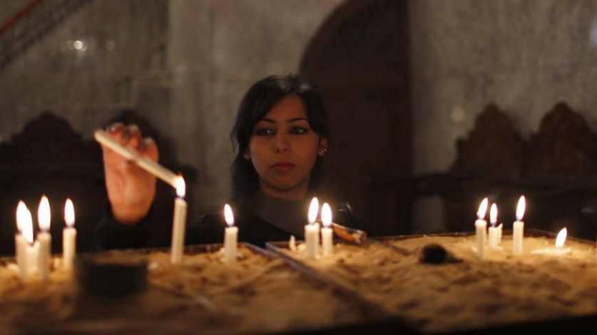 A Palestinian Christian lights candles as she attend a service in Saint Porfirios church in Gaza City December 22, 2013. REUTERS/Mohammed Salem (GAZA - Tags: SOCIETY RELIGION) - RTX16R7G