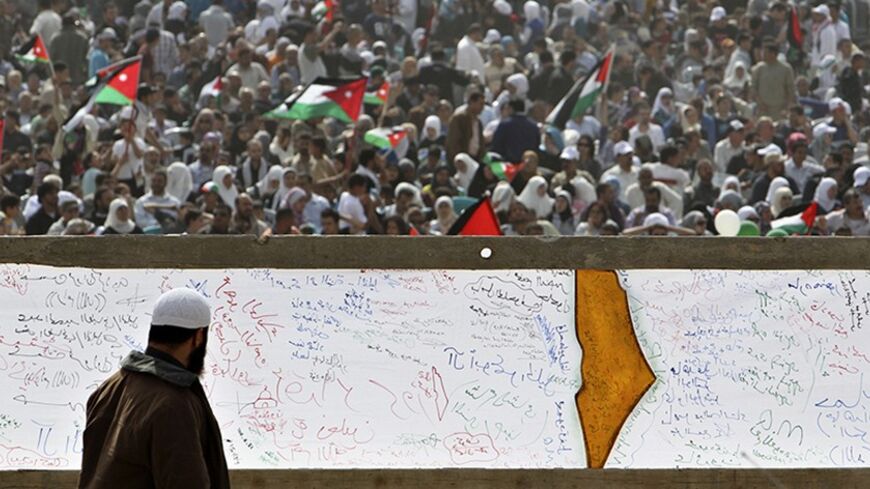 A Palestinian refugee walks past a banner painted with the map of Palestine during a demonstration to mark the 63rd anniversary of "Nakba", Arabic for "Catastrophe", the term used to mark the events leading to Israel's founding in 1948, in Shouneh west of Amman May 13, 2011. Nearly 5,000 Jordanians gathered in the Jordan Valley near the Israeli border to demand an end to the occupation of Palestinian territories. REUTERS/Muhammad Hamed (JORDAN - Tags: POLITICS CIVIL UNREST ANNIVERSARY) - RTR2MDQS