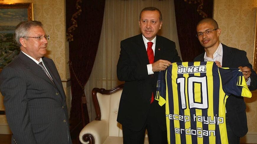 Fenerbahce Chairman Aziz Yildirim (L) and the team's Brazilian captain Alex de Souza (R) pose with Turkey's Prime Minister Tayyip Erdogan during their visit in Ankara in this April 19, 2011 file photo. A Turkish court jailed 15 more people, including top soccer club executives, pending trial on July 7, 2011 as part of a major match-fixing investigation which the prime minister said is staining the country's image. Three executives of champions Fenerbahce, the chairman of Sivasspor and coach of Eskisehirspor