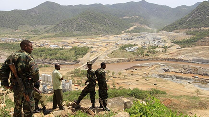 Security guards look at the construction of Ethiopia's Great Renaissance Dam in Guba Woreda, some 40 km (25 miles) from Ethiopia's border with Sudan, June 28, 2013. Egypt fears the $4.7 billion dam, that the Horn of Africa nation is building on the Nile, will reduce a water supply vital for its 84 million people, who mostly live in the Nile valley and delta. Picture taken June 28, 2013. REUTERS/Tiksa Negeri (ETHIOPIA - Tags: POLITICS SOCIETY ENERGY ENVIRONMENT) - RTX115K8