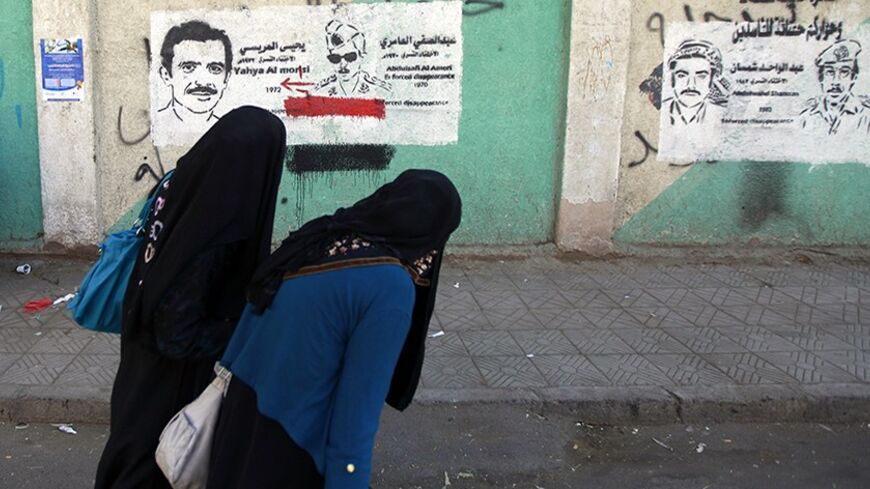 Women walk by a mural of a flag of the Yemen Arab Republic from former North Yemen in Sanaa, December 24, 2013. REUTERS/Mohamed al-Sayaghi (YEMEN - Tags: POLITICS SOCIETY) - RTX16T8G