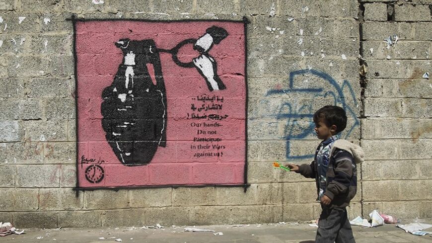 A boy walks past a graffiti depicting a grenade on a street in Sanaa January 9, 2014. The paint is part of a graffiti campaign against armed conflicts in Yemen. REUTERS/Khaled Abdullah (YEMEN - Tags: POLITICS CIVIL UNREST SOCIETY) - RTX177LM