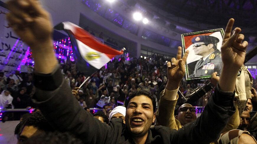 A supporter of Egypt's army chief General Abdel Fatah al-Sisi gestures near an Egyptian flag and an image of Sisi during festivities held to back his potential bid for the presidency at a hall in Cairo stadium January 20, 2014. REUTERS/ Mohamed Abd El Ghany (EGYPT - Tags: POLITICS ELECTIONS MILITARY) - RTX17MVB