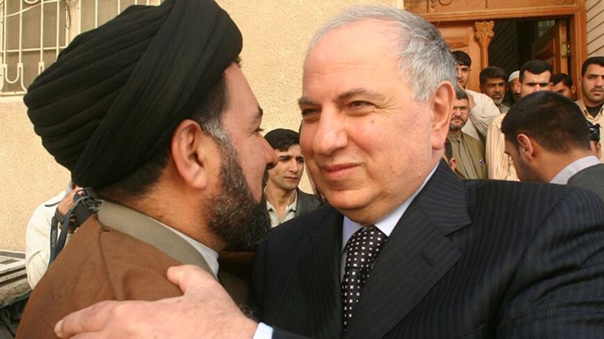Iraqi National Congress candidate Ahmed Chalabi embraces a supporter while campaigning for next week's parliamentary elections in Najaf December 11, 2005. Iraq will close its borders and impose curfews across the country as it ramps up security for Thursday's election, the Interior Ministry said on Sunday. REUTERS/Ali Abu Shish - RTR1AR02