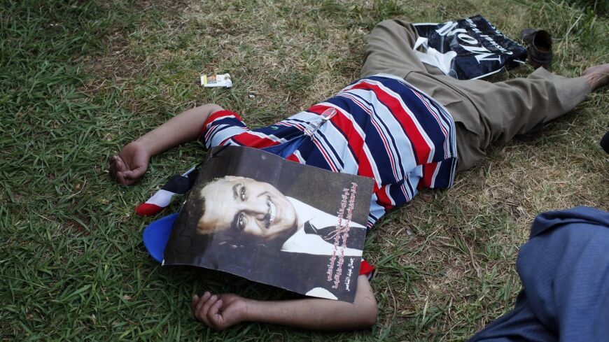 An anti-Mursi protester covers his face with a picture of former Egyptian president Gamal Abdel Nasser as he rests while waiting for other protesters to arrive in front of the presidential palace during a demonstration in Cairo, August 24, 2012. Opponents of Egypt's President Mohamed Mursi scuffled with his supporters on Friday during a demonstration that posed the first test of the Islamist leader's popularity on the street. REUTERS/Asmaa Waguih (EGYPT - Tags: POLITICS CIVIL UNREST) - RTR373G7