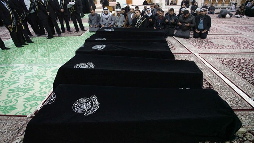 Mourners pray near the coffins of victims killed by a bomb attack at a Shi'ite Muslim village near the Iraqi city of Baquba, during a funeral at the Imam Ali shrine in Najaf, 160 km (100 miles) south of Baghdad, January 25, 2014. Police said that at least six people were killed on Saturday when three mortar bombs hit the village. REUTERS/ Alaa Al-Marjani   (IRAQ - Tags: CIVIL UNREST POLITICS CONFLICT) - RTX17U8H