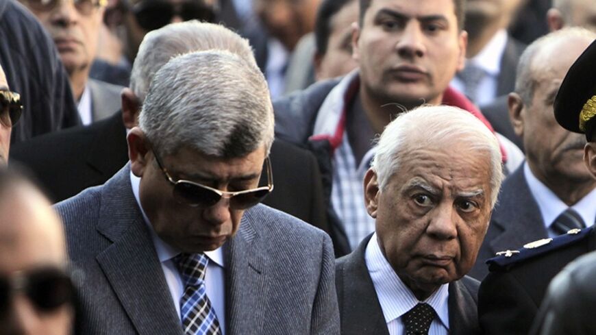 Egypt's Interior Minister Mohamed Ibrahim (L) and Prime Minister Hazem el-Beblawi walk during the funeral service of General Mohamed Saeed, head of the technical office of the minister of interior, with police and Saeed's relatives in Cairo January 28, 2014. Gunmen on a motorbike killed Saeed outside his home in Cairo on Tuesday, putting pressure on the military-backed government as it struggles to contain an Islamist insurgency.  REUTERS/ Mohamed Abd El Ghany (EGYPT  - Tags: POLITICS CIVIL UNREST) - RTX17Y