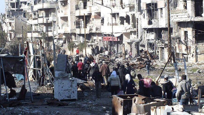 Civilians carry their belongings as they walk towards a meeting point to be evacuated from a besieged area of Homs February 9, 2014. Six hundred people left the besieged ruins of rebel-held central Homs on Sunday, escaping more than a year of hunger and deprivation caused by one of the most protracted blockades of Syria's devastating conflict. The evacuees, mainly women, children and old men, were brought out by the United Nations and Syrian Red Crescent on the third day of an operation during which the aid