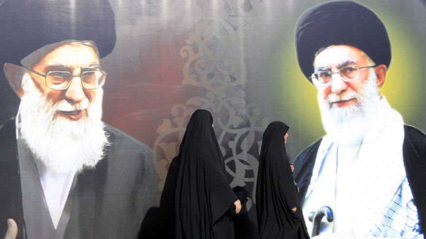 Iraqi women walk past a poster depicting images of Shi'ite Iran's Supreme Leader Ayatollah Ali Khamenei at al-Firdous Square in Baghdad February 12, 2014. An Iraqi daily newspaper stopped publishing after two bombs were planted in the entrance to its headquarters in Baghdad on Monday and after threats from an Iranian-backed Shi'ite militia. Editors and reporters at Assabah AlJadeed said they had received death threats from the influential Asaib al-Haq militia in response to what it had described as an "insu
