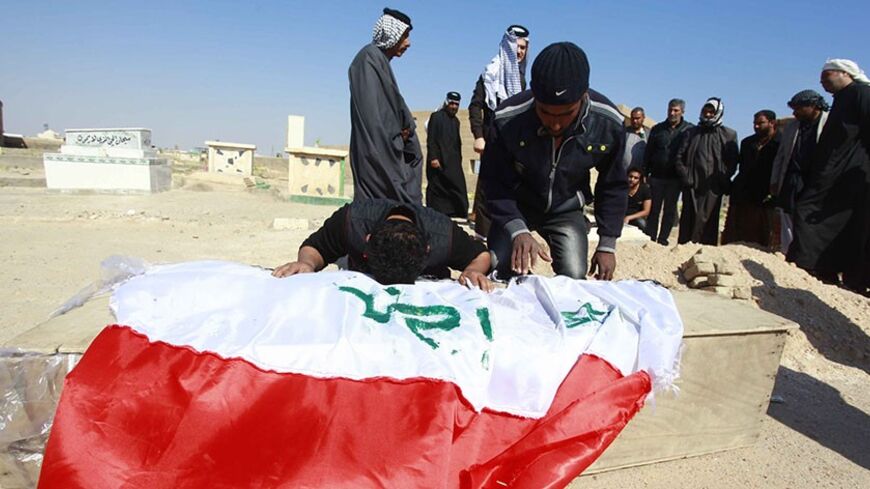 A man reacts over a coffin of a soldier, who was killed during the clashes in Ramadi, during his funeral in Najaf, 160 km (99 miles) south of Baghdad, February 17, 2014. Sunni militancy has been on the rise over the past year, especially in the western province of Anbar, where the army is besieging the city of Falluja, overrun by insurgents on Jan. 1. REUTERS/Alaa Al-Marjani (IRAQ - Tags - Tags: CIVIL UNREST CONFLICT) - RTX18Z5D