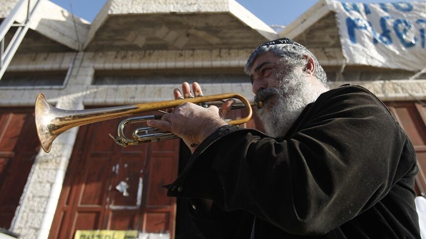 Israeli Ariel Zilber plays the trumpet in front of a house occupied by Jewish settlers in the West Bank city of Hebron November 26, 2008. Hardline Jewish settlers hunkered down in the house in the West Bank flashpoint city of Hebron on Sunday, vowing to resist a court order to quit the property they insist they bought from a Palestinian. About 150 Jewish hardliners, mostly youths, moved into Hebron's settler enclave in the past week to support the 13 families that have been living in the house for a year an