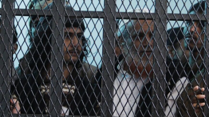 Defendants look out from their holding cell at the court room of a state security court of appeals in Sanaa December 31, 2013. They are among a group of ten suspects charged with involvement in a May 2012 suicide attack on a military parade rehearsal that left 86 police troopers dead and 171 others injured in Sanaa. REUTERS/Khaled Abdullah (YEMEN - Tags: POLITICS CRIME LAW CIVIL UNREST) - RTX16XWS