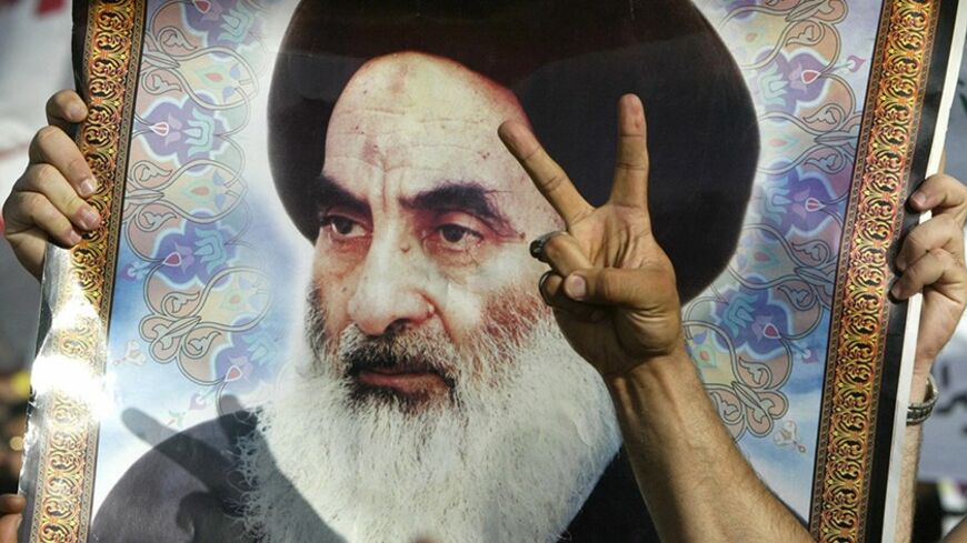 BAGHDAD, IRAQ:  A V-sign for victory is flashed in front of a portrait of religious leader of Iraq's Shiite majority Grand Ayatollah Ali al-Sistani during a march through the streets of Baghdad, 08 June 2004, heeding Sistani's latest call as they headed from the northern district of Al-Shaab toward the coalition's headquarters. The 2000 demonstrators denounced the interim constitution as an instrument of the United States, drafted behind closed doors with the aid of the US-picked and now dissolved Governing
