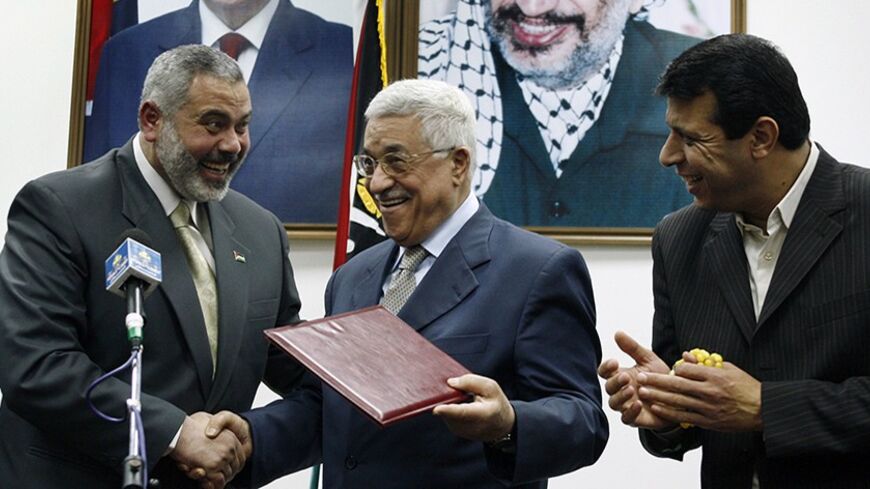 Palestinian President Mahmoud Abbas (C) gives the letter of appointment to Prime Minister Ismail Haniyeh (L) as senior Fatah leader Mohammed Dahlan watches in Gaza February 15, 2007. Abbas formally asked Haniyeh of Hamas on Thursday to form a new unity government and urged him to abide by peace accords signed with Israel. REUTERS/Suhaib Salem (GAZA) - RTR1MG8X