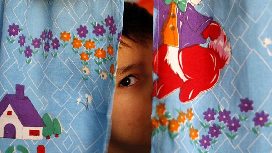 An autistic child peers from between curtains at the Consulting Centre for Autism in Amman, March 30, 2010, one of the few places in the country that helps children with the condition. The world will mark World Autism Awareness Day on April 2.   REUTERS/Ali Jarekji    (JORDAN - Tags: HEALTH EDUCATION) - RTR2C97H
