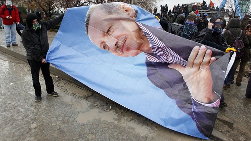 Protesters seize a portrait of Turkey's Prime Minister Tayyip Erdogan during a demonstration against the opening of a new road include a part of the Middle East Technical University campus in Ankara February 25, 2014. Erdogan opened the road across the Middle East Technical University campus and uprooting a large number of trees in the area in Ankara on Tueasday. REUTERS/Umit Bektas (TURKEY - Tags: POLITICS CIVIL UNREST) - RTR3FPP6