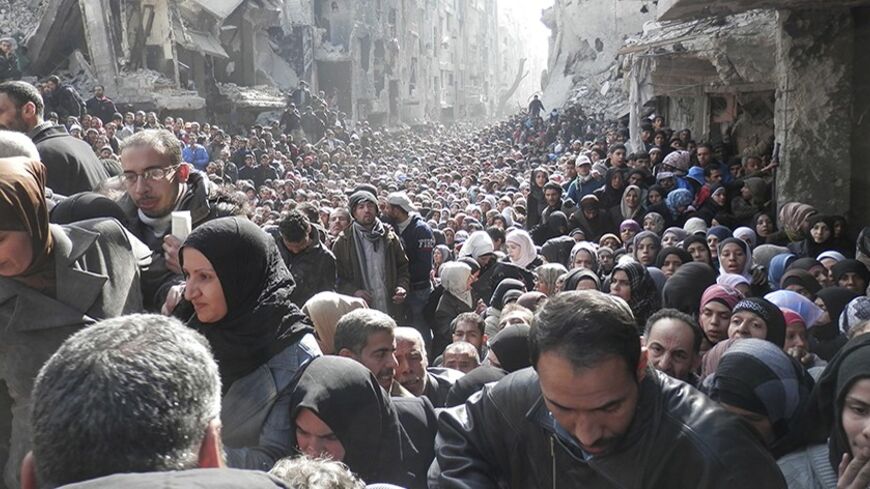 Residents wait to receive food aid distributed by the U.N. Relief and Works Agency (UNRWA) at the besieged al-Yarmouk camp, south of Damascus on January 31, 2014, in this handout picture made available to Reuters February 26, 2014. World powers have passed a landmark Security Council resolution demanding an end to restrictions on humanitarian operations in Syria, but aid workers doubt it has the punch to make Damascus grant access and let stuck convoys deliver vital supplies. The resolution called for the i