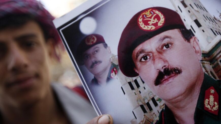 A vendor poses with images of former President Ali Abdullah Saleh (bottom) in Sanaa March 1, 2014. Western diplomats say Saleh and former Vice President Ali Salim Al-Beidh are top candidates of a blacklist by a newly created U.N. sanctions committee for Yemen that will impose asset freezes and travel bans on specific individuals who obstruct the country's political transition or commits human rights violations. REUTERS/Mohamed al-Sayaghi (YEMEN - Tags: SOCIETY POLITICS) - RTR3FUWN