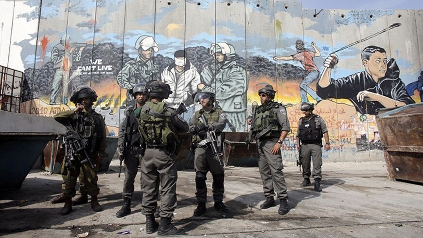 Israeli soldiers and border policemen stand in front of a section of Israel's controversial barrier at Aida refugee camp in the West Bank town of Bethlehem March 24, 2014, where witnesses say Israeli forces confronted stone-throwing Palestinian protesters on Monday. REUTERS/Ammar Awad (WEST BANK - Tags: POLITICS CIVIL UNREST TPX IMAGES OF THE DAY) - RTR3IE2E