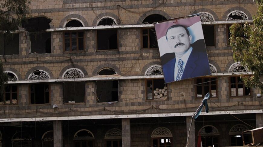 A picture of former Yemeni President Ali Abdullah Saleh hangs on a building of the Standing Committee of the General People's Congress, Saleh's party, in Sanaa, December 17, 2013. The building was damaged during  protests and clashes in 2011. Two years after months of mass protests forced ex-Yemeni President Ali Abdullah Saleh to give up his 33-year rule that brought the country to the brink of civil war, many establishments still bear damages from the conflict. REUTERS/Mohamed al-Sayaghi (YEMEN - Tags: POL