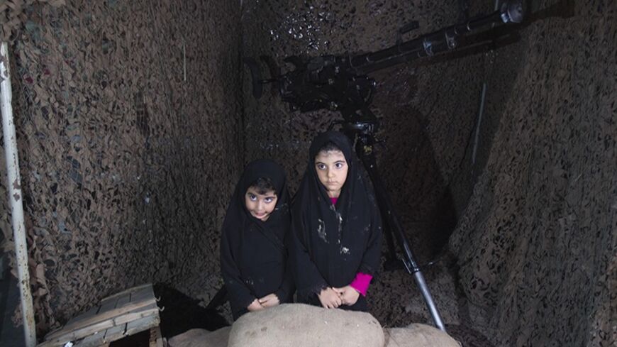 EDITORS' NOTE:  Reuters and other foreign media are subject to Iranian restrictions on their ability to film or take pictures in Tehran.

Two girls pose for a photograph as they sit at a mock shelter at a war exhibition held by Iran's Basij militia and revolutionary guard to mark the anniversary of the Iran-Iraq war (1980-88), also known in Iran as the "Holy Defence", at a Revolutionary Guards military base in south-eastern Tehran September 23, 2010. The base, also known as the Resistance Village, is used a