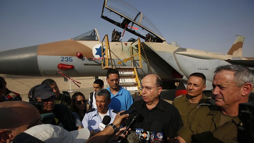 An Israeli Air Force F-15I jet is seen in the background as Israeli Defense Minister Moshe Yaalon (3rd R) speaks to reporters while standing next to Israel's armed forces chief Major-General Benny Gantz (R) and commander of Israel's Air Force Major-General Amir Eshel (4th R) during a presentation at Hatzerim air base in southern Israel April 30, 2013. Israel on Tuesday launched its first targeted attack on a militant in Gaza since a war in November, killing a Palestinian jihadist in an air strike that put f