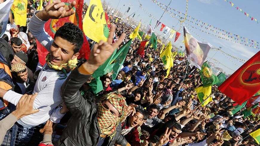 People gesture while others wave Kurdish flags during a gathering celebrating Newroz, which marks the arrival of spring and the new year, in Diyarbakir March 21, 2014. Jailed Kurdish militant leader Abdullah Ocalan of the Kurdistan Workers Party (PKK) called on the Turkish government on Friday to create a legal framework for their peace talks, whose fate is looking increasingly uncertain a year after he called a ceasefire by his fighters. Tens of thousands gathered in Diyarbakir, the largest city in Turkey'