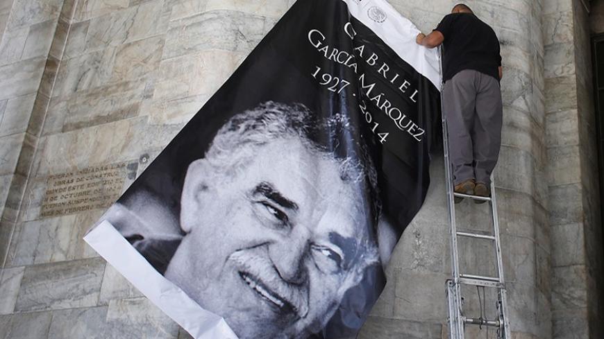 A worker holds a banner with the picture of late Colombian Nobel Prize laureate Gabriel Garcia Marquez at the Bellas Artes palace in Mexico City April 20, 2014. Garcia Marquez, the Colombian author whose beguiling stories of love and longing brought Latin America to life for millions of readers and put magical realism on the literary map, died on Thursday. He was 87. Marquez died at his home in Mexico City, where he had returned from hospital last week after a bout of pneumonia. REUTERS/Tomas Bravo (MEXICO 