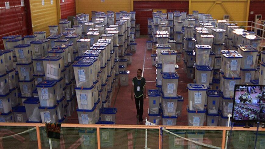 A worker from the Independent High Electoral Commission (IHEC) walks amongst ballot boxes during a vote counting at an analysis centre in Kerbala, south of Baghdad May 2, 2014. Iraq held a democratic vote to choose a leader with no foreign troops present for the first time on Wednesday, as Shi'ite Prime Minister Nuri al-Maliki sought to hold power for a third term in a country again consumed by sectarian bloodshed. The electoral commission said 60 percent of all voters had so far cast a ballot, according to
