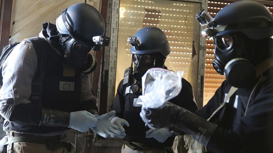 A U.N. chemical weapons expert, wearing a gas mask, holds a plastic bag containing samples from one of the sites of an alleged chemical weapons attack in the Ain Tarma neighbourhood of Damascus August 29, 2013. A team of U.N. experts left their Damascus hotel for a third day of on-site investigations into apparent chemical weapons attacks on the outskirts of the capital. Activists and doctors in rebel-held areas said the six-car U.N. convoy was scheduled to visit the scene of strikes in the eastern Ghouta s