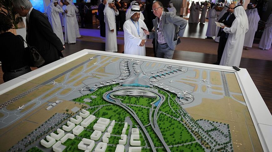 People stand near a scale model of an expanded facility of the Abu Dhabi International Airport during the World Route Development Strategy Summit at Abu Dhabi National Exhibition Centre, September 30, 2012. REUTERS/Ben Job (UNITED ARAB EMIRATES - Tags: TRANSPORT BUSINESS) - RTR38LYY