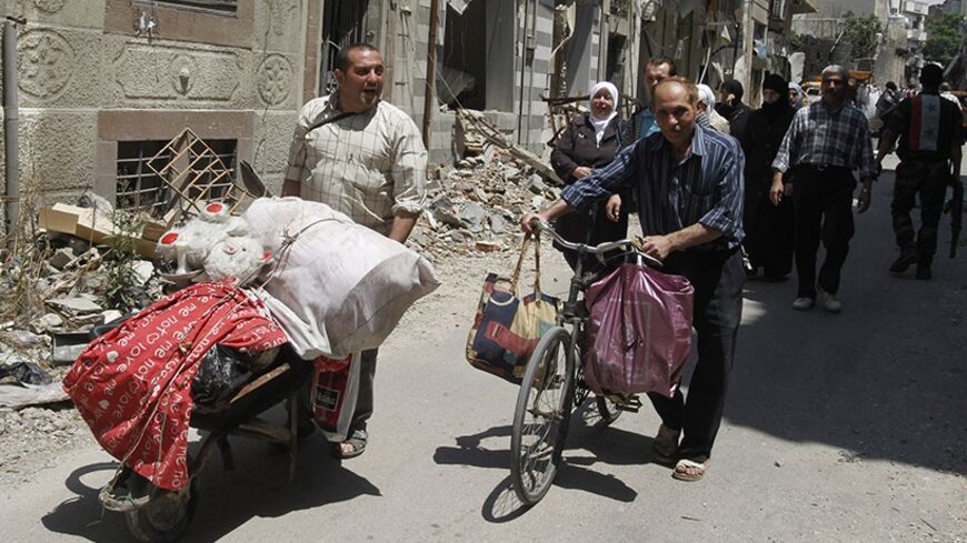 Residents carry belongings from home following the cessation of fighting between rebels and forces loyal to Syria's President Bashar al-Assad, in Homs city May 10, 2014. Hundreds of residents have started to return to Homs after rebels left the city.  REUTERS/Khaled al-Hariri (SYRIA - Tags: POLITICS CONFLICT CIVIL UNREST) - RTR3OL1I