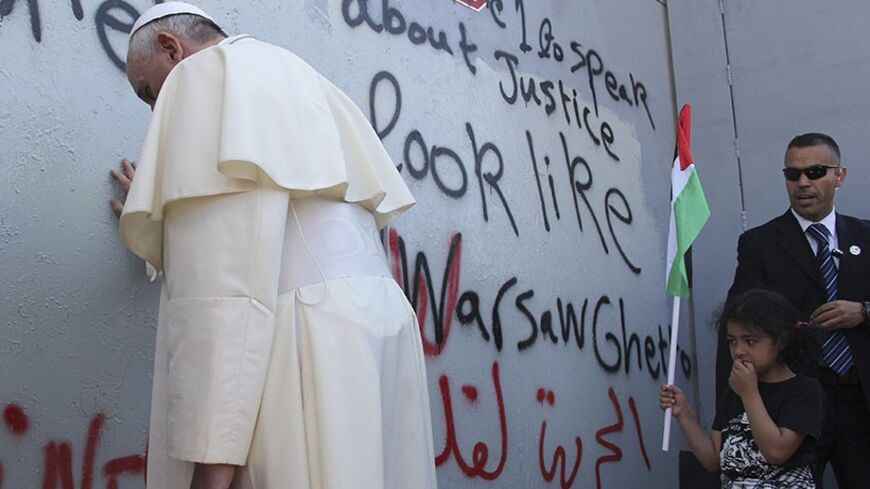 Pope Francis touches the wall that divides Israel from the West Bank, on his way to celebrate a mass in Manger Square next to the Church of the Nativity in the West Bank city of Bethlehem May 25, 2014. Pope Francis made a surprise stop at the hulking wall Palestinians see as a symbol of Israeli oppression on Sunday, minutes after begging both sides to end a conflict that he said was no longer acceptable. REUTERS/Mheisen Amareen (WEST BANK - Tags: RELIGION POLITICS TPX IMAGES OF THE DAY) - RTR3QRA8