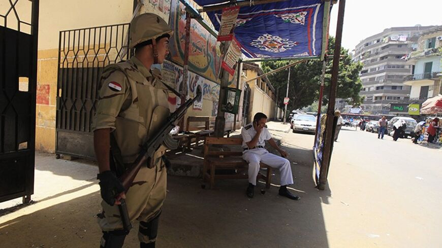 A soldier and policeman wait for voters at a polling station in the El Sayda Zeinab area on the third day of voting in the Egyptian presidential election in Cairo, May 28, 2014. Voting in Egypt's presidential election was slow on Wednesday after polling was extended for a third day in an attempt to boost turnout, raising questions about the level of support for the man forecast to win, former army chief Abdel Fattah al-Sisi.   REUTERS/Amr Abdallah Dalsh (EGYPT - Tags: POLITICS ELECTIONS CIVIL UNREST) - RTR3