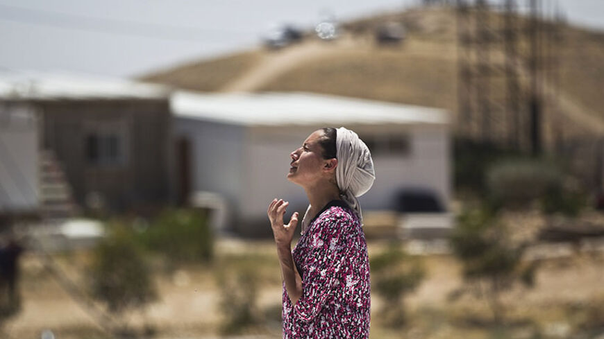 A Jewish settler reacts as she stands atop the roof of a temporary structure before Israeli policemen demolish it in the West Bank Jewish settler outpost of Maale Rehavam, near Bethlehem May 14, 2014.  Some seven structures were razed on Wednesday by Israeli border police officers and no injuries or arrests were made during the incidences, a police spokesman said on Wednesday. The structures were demolished as part of Israel's continuing effort to remove settlements built without government authorization. R