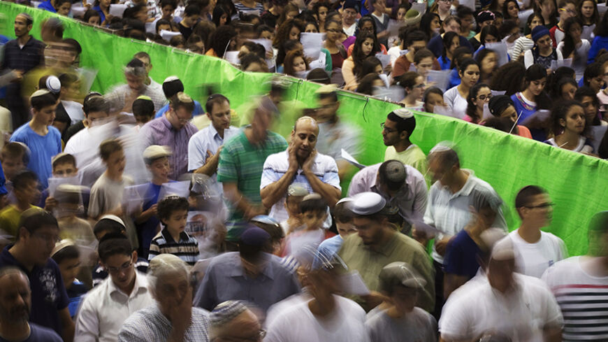 Israeli men and women, separated by a green divider, pray in the town of Elad, home of Eyal Yifrach, one of three missing teenagers, June 16, 2014. Prime Minister Benjamin Netanyahu prepared Israel for a long drawn-out operation to find the three missing teenagers as troops expanded the search into a crackdown on the Islamist group accused of abducting them and arrested dozens of its officials. REUTERS/Finbarr O'Reilly (ISRAEL - Tags: RELIGION POLITICS CIVIL UNREST) - RTR3U421