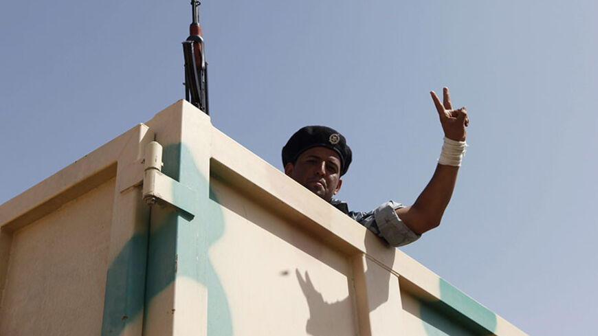 A Shiite volunteer, who has joined the Iraqi army to fight against the predominantly Sunni militants from the radical Islamic State of Iraq and the Levant (ISIL) who have taken over Mosul and other northern provinces, gestures from a truck in Baghdad, June 18, 2014. The United States is contemplating talks with its arch-enemy Iran to support the Iraqi government in its battle with Sunni Islamist insurgents who routed Baghdad's army and seized the north of the country in the past week.  REUTERS/Ahmed Saad (I