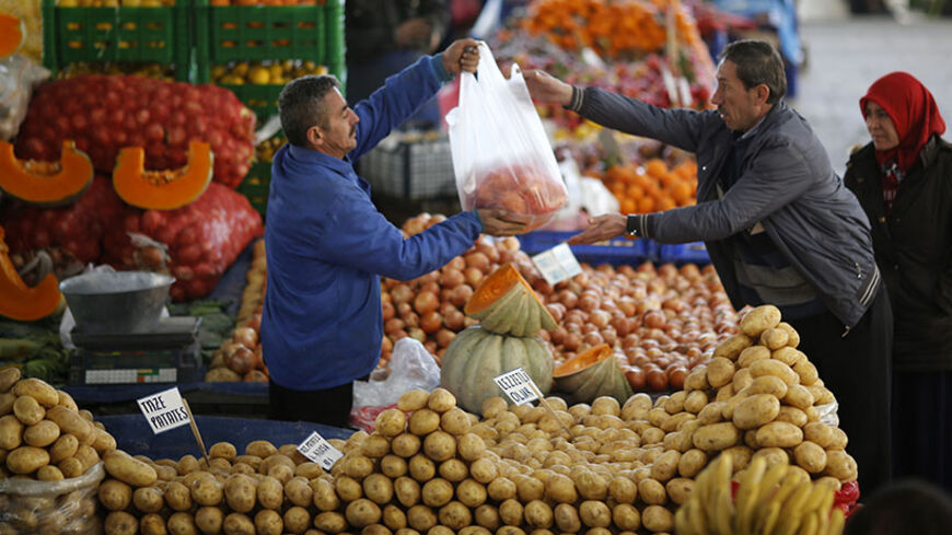 A vendor sells potatoes and other vegetables to a customer in an open market in central Ankara February 5, 2014. The humble potato has become a factor in Turkey's political and economic turmoil as prices of the staple soar, hurting the living standards of poorer Turks just before the ruling AK Party's toughest election test in a decade. At a market in the lower-income Istanbul suburb of Kucukcekmece, potatoes sell for between 3 and 4 lira ($1.33 and $1.77) a kilogramme, up from slightly more than 1 lira at 