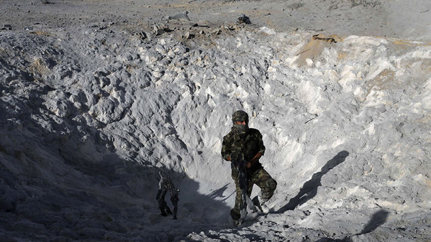 A Palestinian militant inspects a crater caused by what police said was an Israeli air strike in Khan Younis in the southern Gaza Strip June 29, 2014. Israeli army said on Sunday it targeted "terror sites" including, concealed rocket launchers and weapon manufacturing sites in response to earlier rockets fired from Gaza into Israel.  A rocket fired from the Gaza Strip struck a factory in southern Israel on Saturday, setting it on fire, but Israeli officials said there were no serious injuries. REUTERS/Ibrah