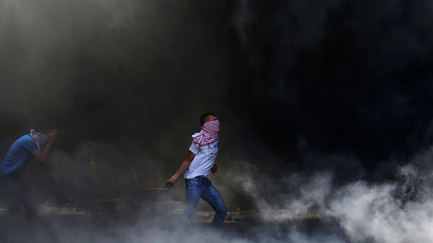 A Palestinian prepares to hurl a stone as he stands in a cloud of smoke from tyres set ablaze during clashes with Israeli police in Shuafat, an Arab suburb of Jerusalem July 2, 2014. The discovery of a body in a Jerusalem forest on Wednesday raised suspicions that a missing Palestinian youth had been killed by Israelis avenging the deaths of three abducted Jewish teens. Rock-throwing Palestinians clashed with Israeli forces in Jerusalem after the news, but no serious injuries were reported. REUTERS/Baz Ratn