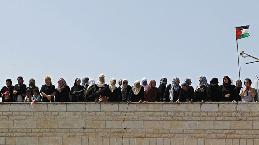 Palestinian women watch from a rooftop as the body of 16-year-old Mohammed Abu Khudair is carried during his funeral in Shuafat, an Arab suburb of Jerusalem July 4, 2014. Palestinians infuriated at the kidnap and killing of Abu Khudair they blame on far-right Jews, clashed with Israeli police in Jerusalem on Friday, while cross-border shelling in the Gaza Strip abated under Egyptian mediation. REUTERS/Ammar Awad (JERUSALEM - Tags: POLITICS CIVIL UNREST OBITUARY) - RTR3X41S