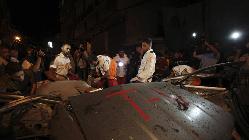 Palestinian medics inspect the remains of a car, which police said was hit in an Israeli air strike, in Gaza City July 9, 2014. An Israeli aircraft targeted a civilian car in the center of Gaza City's busiest shopping street on Wednesday night and at least one person in the car, the driver, was killed, medics said.Video of the destroyed car showed it had large red stickers that read "TV". The killed driver, Hamed Shehab, 30, worked for the Gaza-based news website Media 24. A Media 24 journalist told Reuters